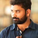 Farm to Home - Nature’s Best & Pure, at your Doorstep A thoughtful man with a beard and blue shirt posing indoors, displaying a stylish watch.